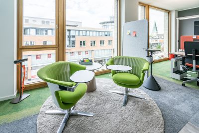 Grüne Loungesessel mit Schreibtabler und rundem Besitelltisch auf rundem grauen Teppich