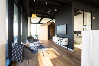 Zwei Loungesessel mit Fußhocker und rundem Beistelltisch vor einem Sideboard mit darüber installiertem Bildschirm