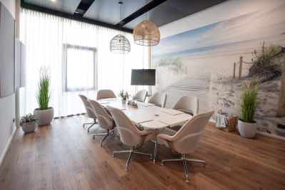 Designorientierte Konferenzraumlösung mit Besprechungstisch und Konferenzsessel in Erdtönen mit einer großformatigen Fototapete mit Dünenlandschaft