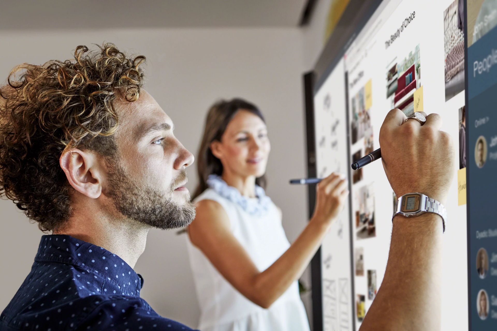 Mann und Frau arbeiten parallel an einem interaktiven Display