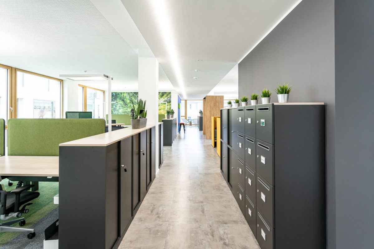 Sinnvolle Stauraumlösung in Form von Schiebetürenschränken und persöhnliche Postfächer als Raumteiler in einer offenen Bürostruktur