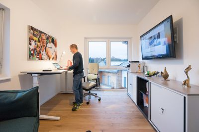 Elektromotorisch höhenverstellbarer Schreibtisch mit einem ergonomischen Bürodrehstuhl für das Home - Office