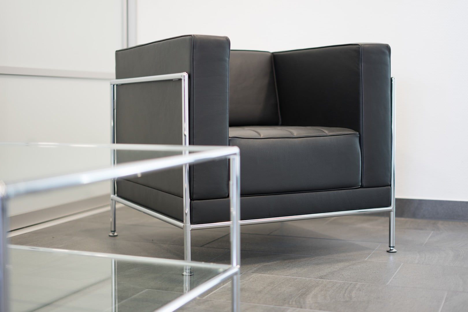 Sessel mit schlanker Linie und elegantem Design kombiniert mit einem Glastisch