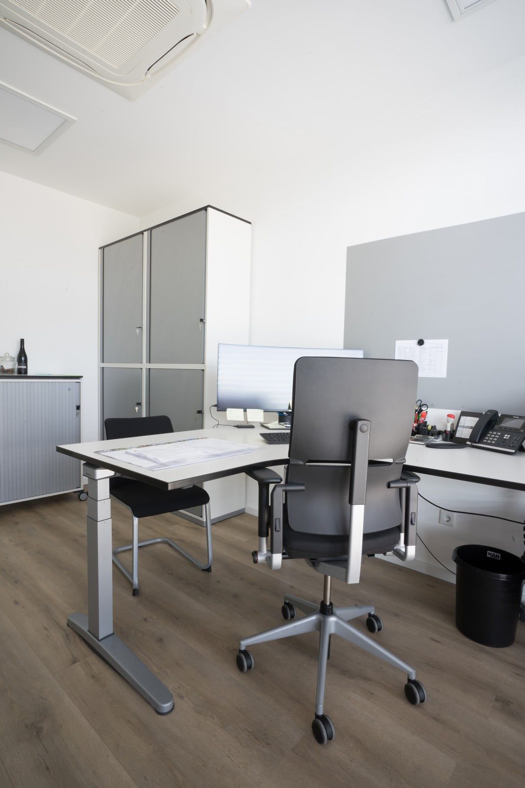 Höhenverstellbarer Einzelarbeitsplatz mit ergonomischen Bürodrehstuhl und durchdachte Stauraumlösung
