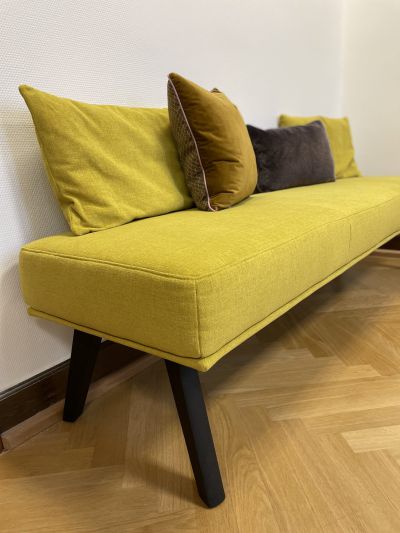 Gelbe schlichte Sitzbank mit verschiedenfarbig akzentuierten Kissen